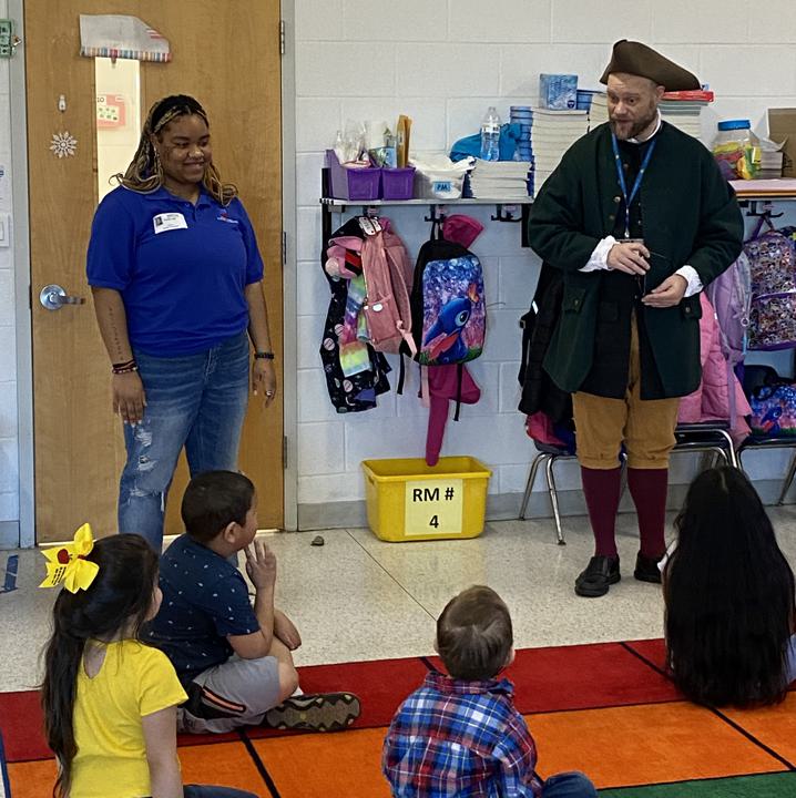 Educator in Colonial Costume speaking to a classroom of children