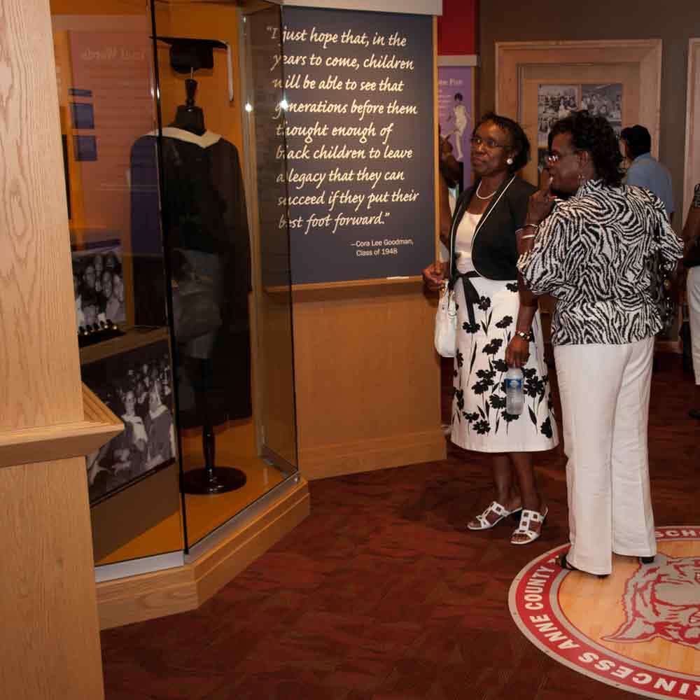 Visitors Looking at a Graduation Display Case of Cap and Gown